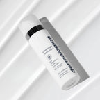 ダーマロジカ P-ブライト モイスチャライザー SPF50 — 白い布の上に斜めに置かれた製品ボトルのスタイリングショット | 日焼け止め・保湿クリーム